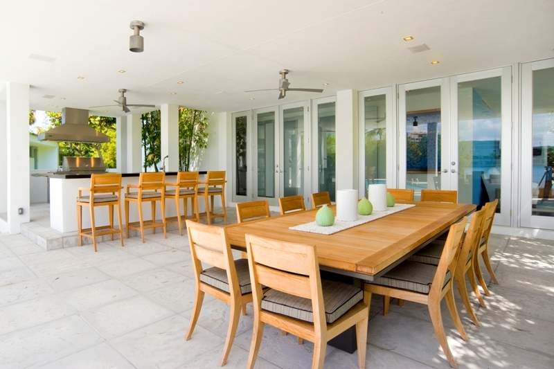 Large covered outdoor dining area with ten-person table and a bar